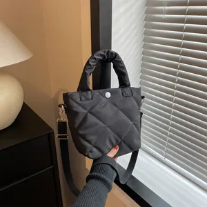 Detail der schwarzen Stepptasche mit plissiertem Griff und weißem Druckknopfverschluss