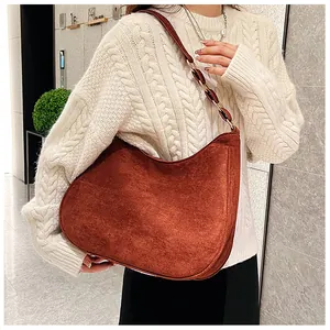 Detail van steenrode suède hobo tas met een elegante schouderband van metalen ketting