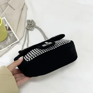 Detail showing black suede mini bag with shimmering rhinestones and silver chain strap