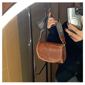 Détail du sac bandoulière marron vintage avec large sangle à motifs géométriques