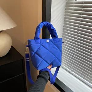 Detail der dunkelblauen Stepptasche mit gepolstertem Griff und weißem Kontrastknopf