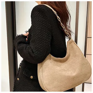 Detail van beige hobo-tas van mat leer met metalen ketting en een leren schouderriem
