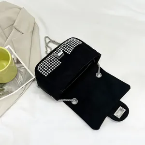 Detail of black velvet crossbody bag featuring silver studs and metal chain strap