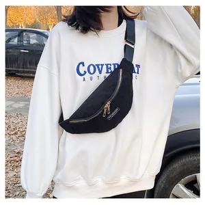 Detail of black corduroy crossbody bag featuring dual gold zippers and fashion label