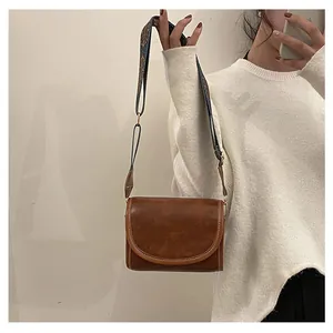 Sac bandoulière marron chic avec large sangle ethnique bleue portée par un mannequin
