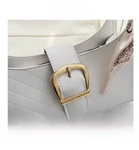 Detail of white quilted handbag with gold buckle and a decorative patterned silk scarf