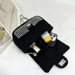 Close-up of black suede crossbody bag featuring silver studs and metal chain strap