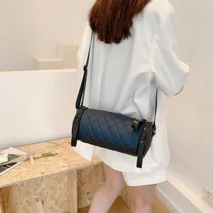 Navy quilted cylinder crossbody bag with wide adjustable strap worn by model