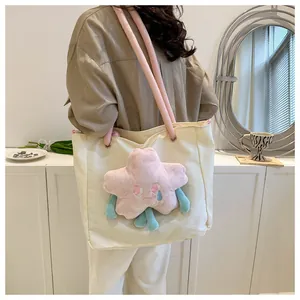 Dettaglio borsa tote in tela crema con ciondolo a stella rosa e tracolle tubolari rosa