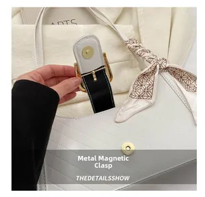 Detail of white quilted bag featuring a gold magnetic snap and floral silk scarf handle