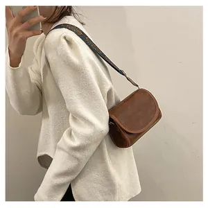 Détail du sac bandoulière en similicuir marron avec une large sangle brodée