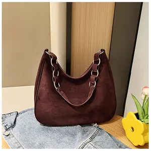 Detail van bordeauxrode matte leren tas met metalen ringketting op houten blad