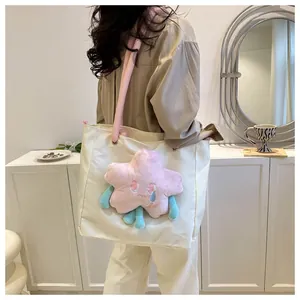 Dettaglio della borsa tote in tela bianco sporco con peluche stella rosa sulla spalla