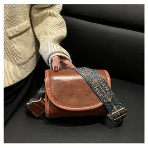 Détail du sac bandoulière en similicuir marron avec large sangle ethnique jacquard