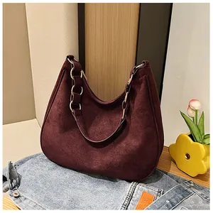 Detailopname van de wijnrode suède hobo tas met metalen ring op een denim achtergrond