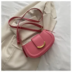 Detail of pink saddle bag with golden crescent metal clasp on a stylish white suit jacket