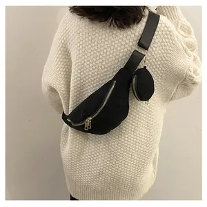 Close-up of black textured crossbody bag with gold zippers and round coin purse pendant