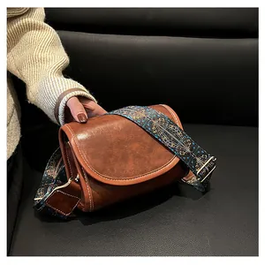 Détail d'un sac besace marron en cuir avec bandoulière ethnique et coutures apparentes