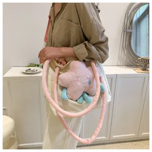 Dettaglio di una borsa tote in tela beige con manici rosa e ciondolo a stella morbida