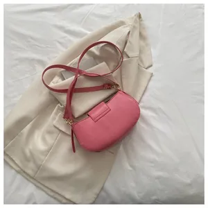 Detailed view of pink semi-circle crossbody bag on a beige blazer with golden buckle