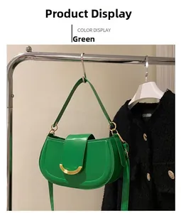 Detail of green saddle bag with gold crescent buckle on a tweed jacket background