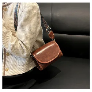 Détail du sac bandoulière vintage marron avec une large sangle en tissu style ethnique