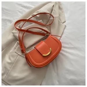 Detailed macro view of orange saddle bag with gold metal buckle on beige blazer