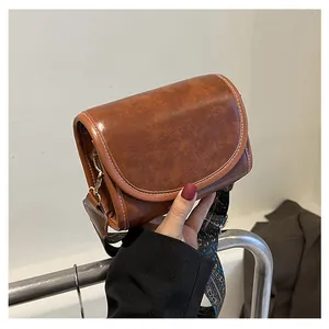 Détail du sac bandoulière marron vintage avec large sangle ethnique et coutures blanches