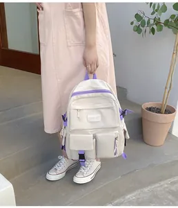 Vue détaillée du sac à dos en nylon crème et violet avec de multiples poches de rangement