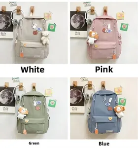 Quattro zaini per la scuola colorati in bianco, rosa, verde e blu con graziosi ciondoli