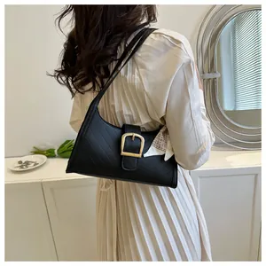 Detail of black quilted shoulder bag with golden buckle and geometric silk scarf accent
