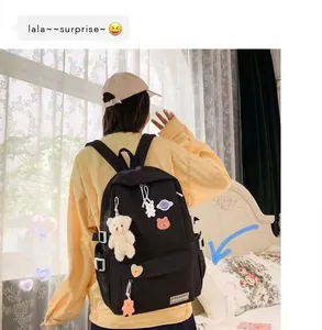 Dettaglio dello zaino in nylon nero con toppe a cartoni animati e ciondolo a orsetto