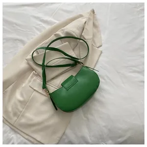Detail view of a bright green crescent saddle bag on an ivory blazer jacket