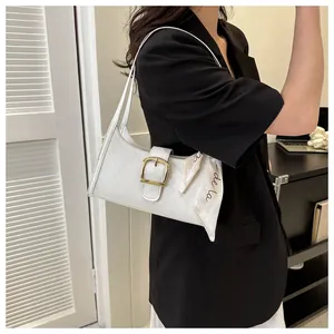 Close-up of white quilted baguette bag with gold buckle and chic silk scarf detail