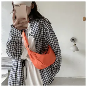 Modelo con bolso bandolera de nailon naranja brillante en forma de media luna y correa ajustable