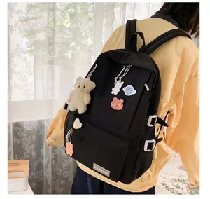 Dettaglio dello zaino in nylon impermeabile con ciondolo a orso e toppe decorative
