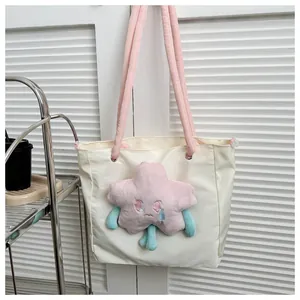 Dettaglio della borsa tote crema con peluche a stella rosa e manici morbidi vicino alla finestra