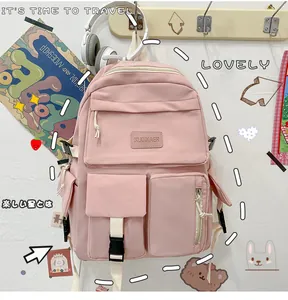 Détail d'un sac à dos scolaire rose montrant plusieurs poches et un tissu en nylon