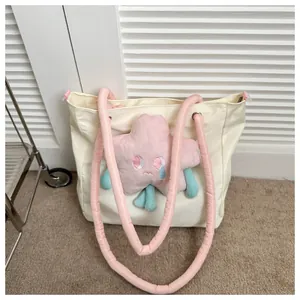 Dettaglio della borsa tote crema con peluche a stella rosa e tracolla morbida imbottita