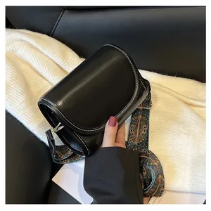 Détail du sac bandoulière noir avec coutures blanches contrastées et sangle ethnique