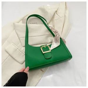 Detail of green quilted PU shoulder bag with gold buckle and decorative silk scarf wrap