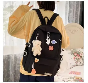 Dettaglio dello zaino in nylon nero con graziosi ciondoli di peluche e spille decorative