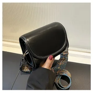 Détail du sac en cuir PU noir avec coutures contrastées et large bandoulière ethnique