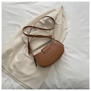 Detail of a brown leather saddle bag featuring a curved silhouette and metal hardware
