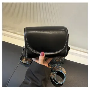 Détail d'un sac bandoulière en cuir noir avec surpiqûres blanches et sangle bohème