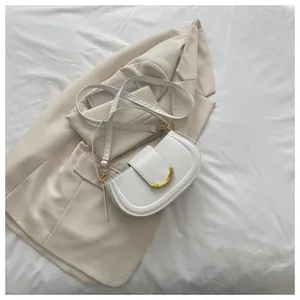 Detail of white leather saddle bag showing refined golden crescent moon buckle closure