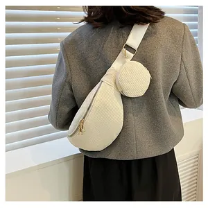 Detailed side view of off-white corduroy crossbody bag with a round coin purse attached