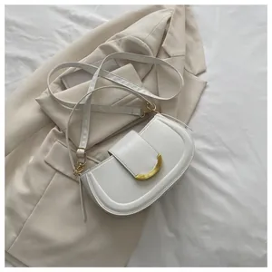 Detail of white minimalist saddle bag with polished gold horseshoe metal buckle