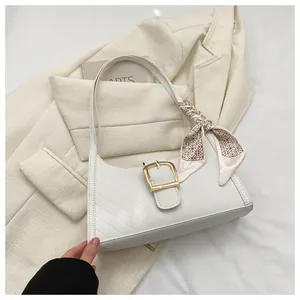 Detailed shot of white quilted shoulder bag featuring gold buckle and silk scarf accent