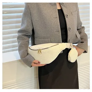 Detail of off-white corduroy crossbody bag with matching round coin purse on grey suit
